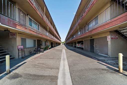A long, narrow road separates two rows of apartment buildings.