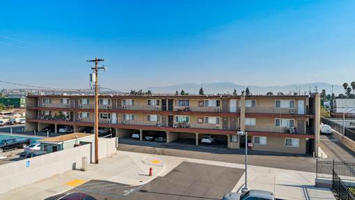 A parking lot in front of a multi-story apartment building.