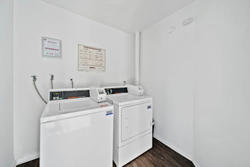 A white wall with a washing machine and dryer in front of it.