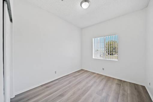 A room with a window covered by blinds and a wooden floor.