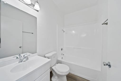 A white bathroom with a toilet, sink, and bathtub.