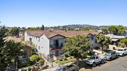 A sunny day in a residential area with houses and parked cars.