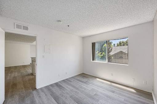 A room with a window showing a house and trees outside.