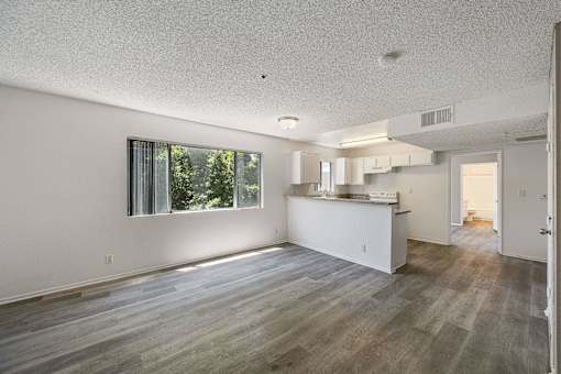 A spacious kitchen and living room with wood flooring and white walls.