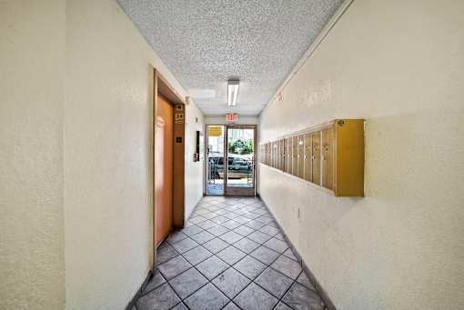 A long hallway with a brown door and a white wall.