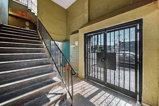 A staircase with a metal railing leads to a black gate.