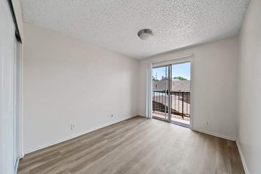 A room with a sliding glass door leading to a balcony.