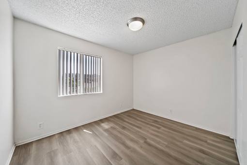 A room with a window and wooden flooring.