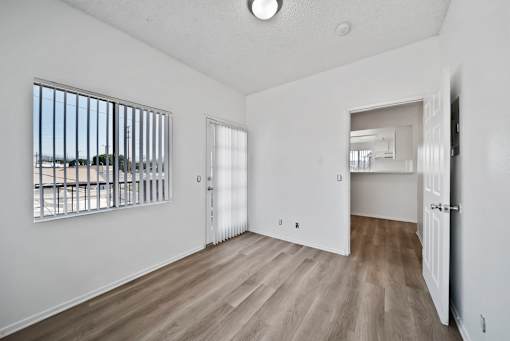A room with a window, a door, and a wooden floor.