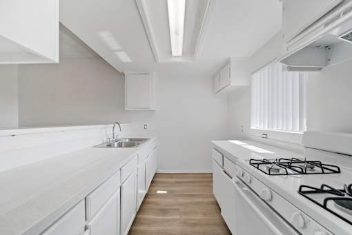 A modern kitchen with white cabinets and a white stove top oven.