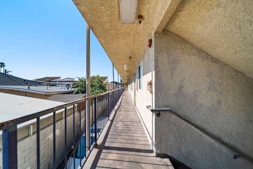 A long concrete staircase with a metal railing on the left side and a wall on the right side.