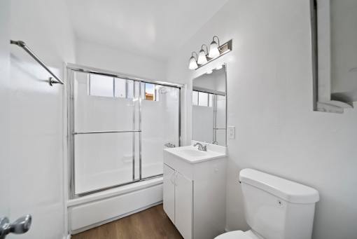 A white bathroom with a toilet, sink, and mirror.