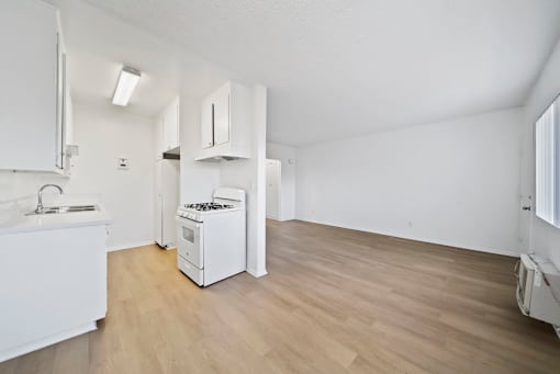 A kitchen with white cabinets and a wooden floor.
