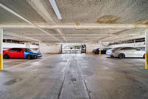 A parking garage with a red car on the left and a white car on the right.