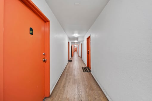 A long hallway with orange doors and white walls.