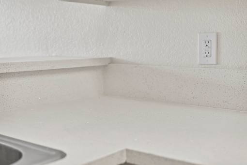 A white electrical outlet is mounted on a white wall.