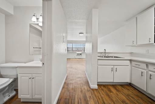 A white bathroom with a wooden floor and white cabinets.