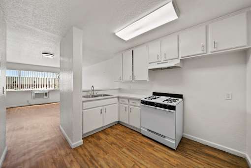 A kitchen with white cabinets and a stove top oven.