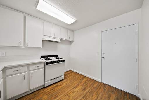A kitchen with white cabinets and a stove top oven.