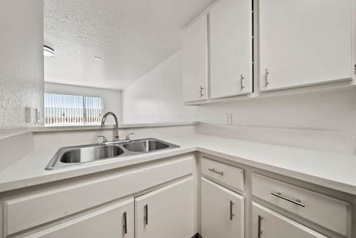 A white kitchen with a sink and cabinets.
