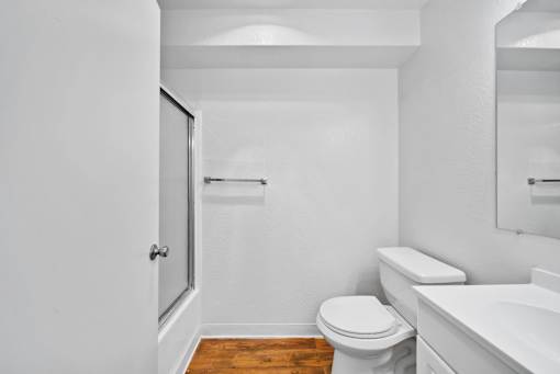 A white bathroom with a toilet, sink, and mirror.