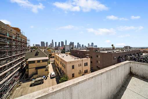 A cityscape is visible in the distance from a rooftop view.