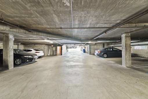A parking garage with cars parked on both sides of the aisle.