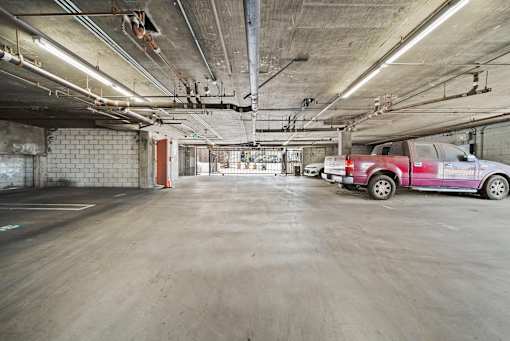 A red car is parked in a large, empty parking garage.