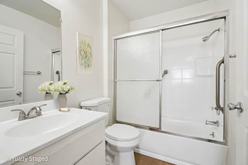 A white bathroom with a toilet, sink, and shower.