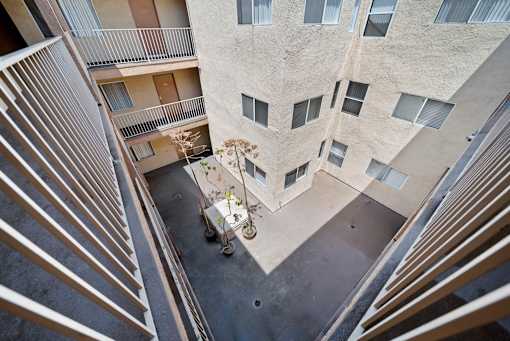 A view from above of a courtyard between two buildings with a small tree and a planter.