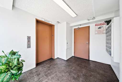 A hallway with two doors and a sign that says "Elevator".