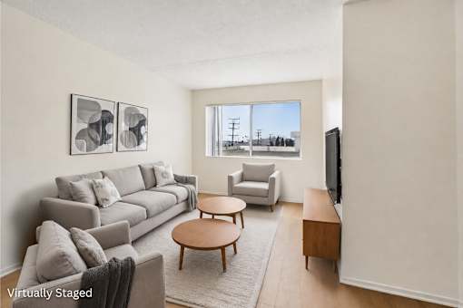 A living room with a grey couch, a coffee table, and a television.