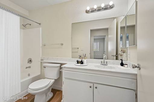 A white bathroom with a toilet, sink, mirror and tub.