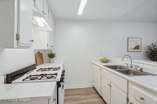 A kitchen with a stove top oven, a sink and plenty of storage