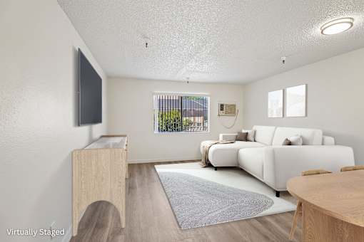 A large living room with a wall AC unit and a window