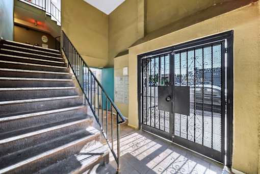 A staircase with a metal railing leads to a black gate.