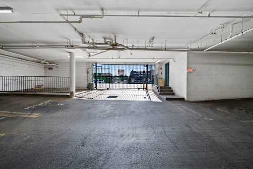 A large, empty parking garage with a view of the city through the open door.