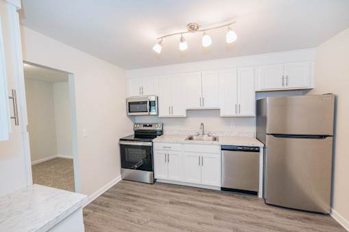 A kitchen with white cabinets and stainless steel appliances at Kings Gate West Apartments, New York, 13031