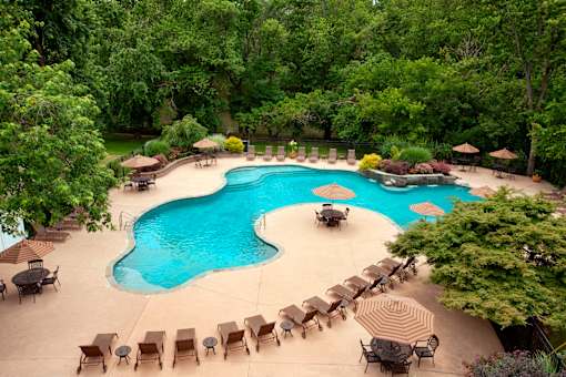 A large outdoor swimming pool surrounded by trees and lounge chairs. at Rivercrest Apartments, Piscataway , NJ, 08854