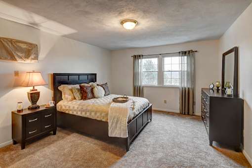 A bedroom with a large bed and a nightstand with a lamp at Kings Gate West Apartments, New York