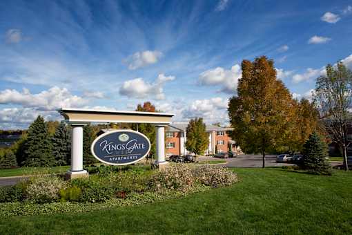 A Kings Gate Apartments sign is in front of a building and trees at Kings Gate West Apartments, Camillus 13031