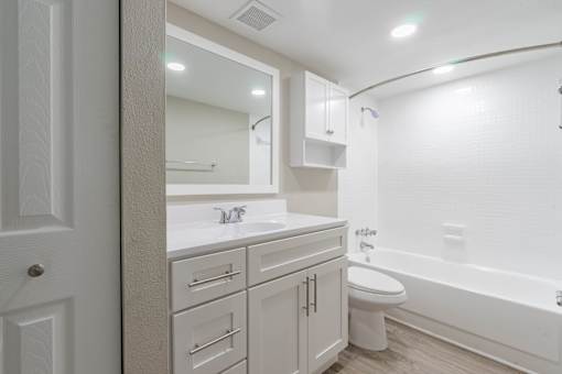 A white bathroom with a toilet, sink, and bathtub at Imperial Gardens Apartments, Clearwater