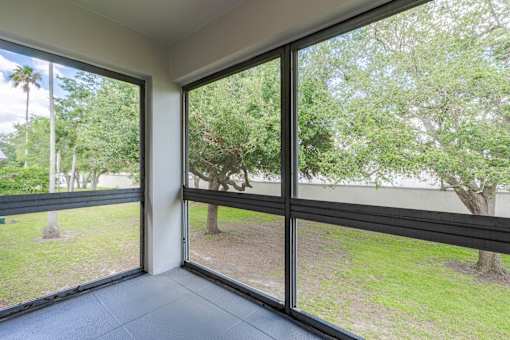 A balcony with glass doors leading to a green outdoor area at Imperial Gardens Apartments, Clearwater, Florida