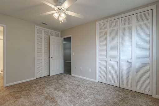 A room with a ceiling fan and three white closet doors at Imperial Gardens Apartments, Clearwater