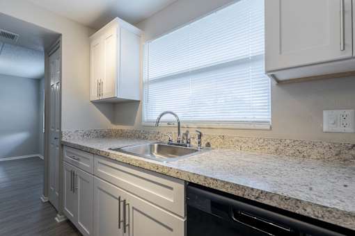 A kitchen with a granite countertop and a dishwasher at Imperial Gardens Apartments, Clearwater, FL