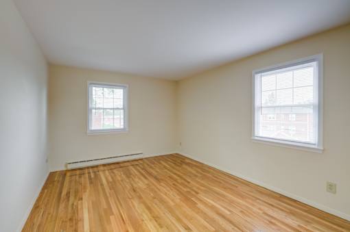 A room with wooden floors and two windows at Rivercrest Apartments, Piscataway , New Jersey