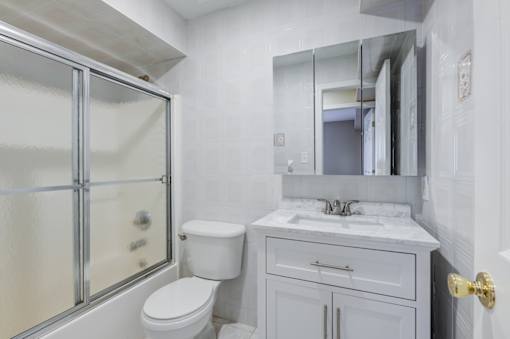 A white bathroom with a toilet, sink, and shower at Seaview Apartments in Staten Island, NY, 10305