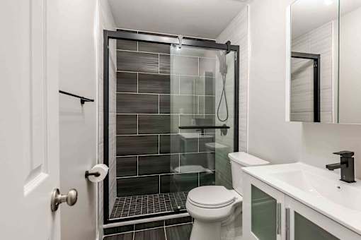 A white toilet sits next to a walk-in shower in a bathroom at Seaview Apartments in Staten Island, NY, 10305
