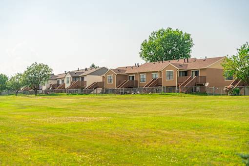 A row of houses with a green field.