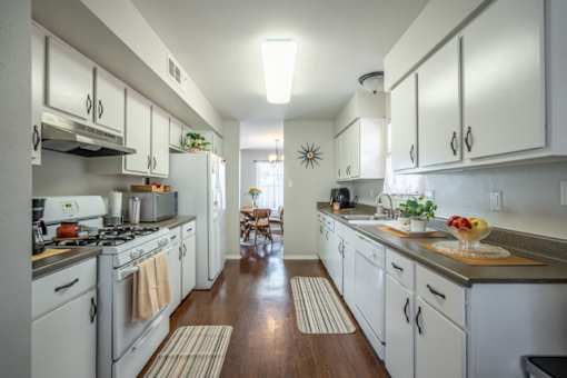 A kitchen with white cabinets and a wooden floor.